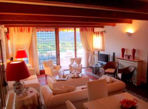 sala de estar con muebles blancos y ventana grande en Villa Carola at Punta Ala (Sea & Golf Club View), en Punta Ala