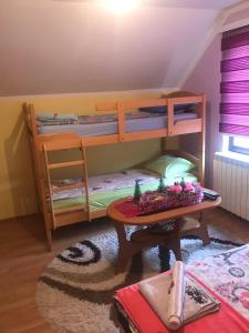 a room with two bunk beds and a table at Apartmani NINA Zlatar in Nova Varoš