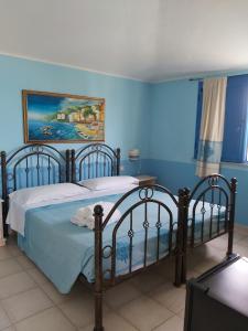a bedroom with two beds and a blue wall at Hotel Baia Cea in Bari Sardo