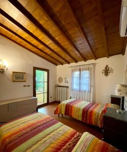 2 letti in una camera con soffitti in legno di Villa Elisa a Scarperia