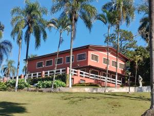 a red building with palm trees in front of it at Pousada Solar das Palmeiras in Joanópolis