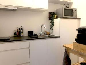 una cucina con armadi bianchi, lavandino e forno a microonde di Het Veldhuis ad As