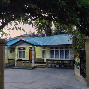 a yellow brick house with a blue roof at HeiJo's Homestay in Jowai