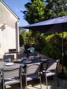 een buitentafel met een blauwe parasol en stoelen bij Gîte de la Cuve in Huisnes-sur-Mer