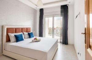 1 dormitorio con 1 cama blanca grande con almohadas azules en Appartement 3 CHAMBRES ensoleillé à 5 min de la plage El Jadida, en El Jadida