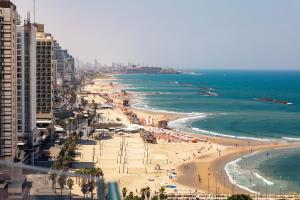 een uitzicht op een strand met mensen en de oceaan bij Carlton Tel Aviv Hotel – Luxury on the Beach in Tel Aviv