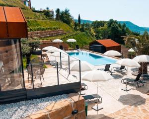 a swimming pool with chairs and umbrellas next to a building at Wine Paradise - Glamping resort in Marezige