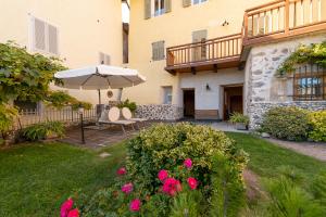 un patio avec un parasol et quelques fleurs roses dans l'établissement Albertini Vacanze, à Brez