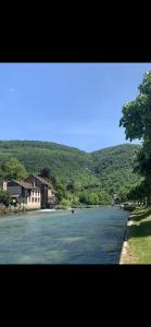 a river with houses on the side of a mountain at Maison de campagne in Vuillafans