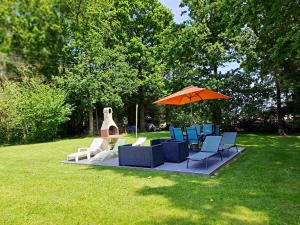 un groupe de chaises et un parasol sur une pelouse dans l'établissement Maison de 3 chambres avec jardin amenage et wifi a Saint Alban a 3 km de la plage, à Saint-Alban