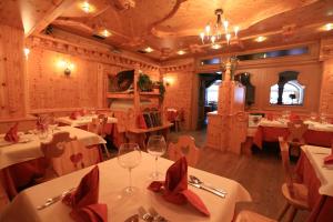 un restaurante con mesas blancas y servilletas rojas en Hotel Laurin, en Canazei