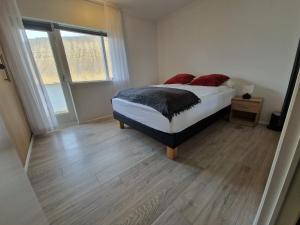 a bedroom with a bed and a wooden floor at Sólgarður Guesthouse in Bíldudalur