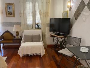 ein Wohnzimmer mit einem TV und einem weißen Stuhl in der Unterkunft Studio Apartment Naya in Mali Lošinj