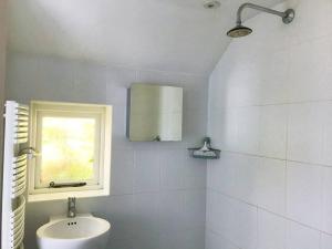 a white bathroom with a sink and a window at Cider Mill Cottage in Alderton