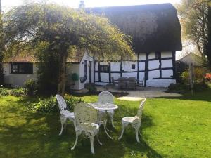 a table and chairs in front of a house at Cider Mill Cottage in Alderton
