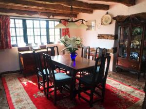 a dining room table with a vase of flowers on it at Cider Mill Cottage in Alderton