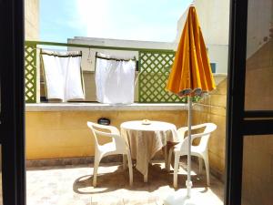 una mesa con sillas y una sombrilla en el balcón en Flat Cloud 9, en Żebbuġ