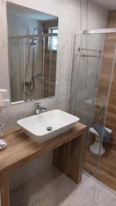 W łazience znajduje się umywalka i przeszklony prysznic. w obiekcie Hotel Nydri Beach w mieście Nydri