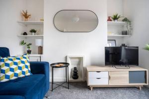 a living room with a blue couch and a tv at The Crown, Modern and Stylish Home from Home in Darlington