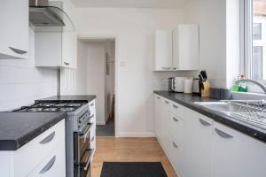 a white kitchen with a stove and a sink at The Crown, Modern and Stylish Home from Home in Darlington