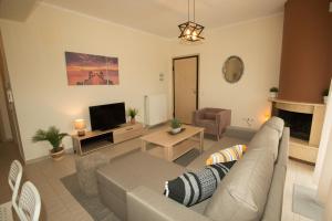 a living room with a couch and a tv at Potamos Luxury Apartment in Epanomi