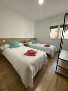 una camera con due letti con asciugamani rossi di Apartamento NyA Zamora a Zamora