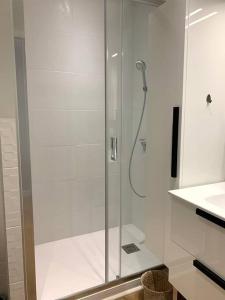 La salle de bains est pourvue d'une douche avec une porte en verre. dans l'établissement T2 avec garage possible, port et plage à moins de 5 minutes à pied !, à Bandol