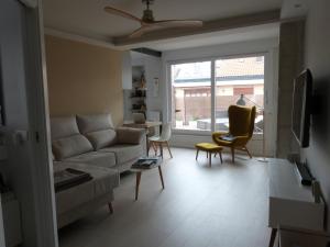 ein Wohnzimmer mit einem Sofa, Stühlen und einem Fenster in der Unterkunft Rooftop Suites Vitoria in Vitoria-Gasteiz