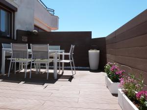 eine Terrasse mit einem Tisch, Stühlen und Blumen in der Unterkunft Rooftop Suites Vitoria in Vitoria-Gasteiz