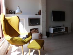 ein Wohnzimmer mit einem gelben Stuhl und einem TV in der Unterkunft Rooftop Suites Vitoria in Vitoria-Gasteiz