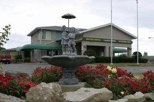 a statue of a woman with an umbrella in a flower garden at Seven Oakes Motel in Kingston