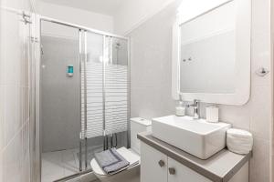 a white bathroom with a sink and a shower at Aroma Accommodations in Kivérion