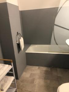 La salle de bains est pourvue d'une baignoire, d'un lavabo et d'une serviette. dans l'établissement HOTEL BON ACCUEIL, à Oyonnax