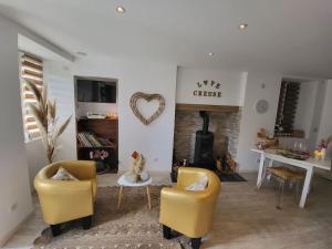 ein Wohnzimmer mit 2 gelben Stühlen und einem Kamin in der Unterkunft Une petite maison seulement pour 2 