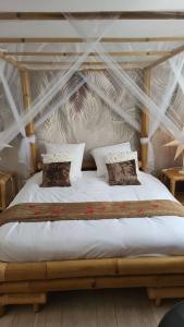 Schlafzimmer mit einem Bett mit weißer Bettwäsche und Kissen in der Unterkunft Une petite maison seulement pour 2 
