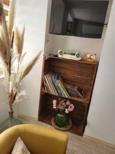 ein Wohnzimmer mit einem TV und einer Vase mit Blumen in der Unterkunft Une petite maison seulement pour 2 