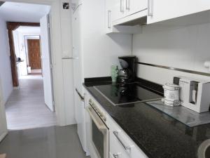 uma cozinha com armários brancos e um balcão preto em San Antonio Suites Vitoria em Vitoria-Gasteiz