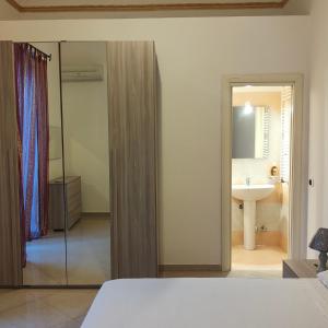 - une chambre avec un lit, un lavabo et un miroir dans l'établissement Appartamento Corso Savoia, à Rosolini