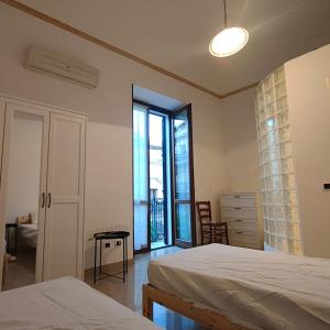 - une chambre avec 2 lits et une grande fenêtre dans l'établissement Appartamento Corso Savoia, à Rosolini