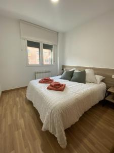 a white bedroom with a large bed with two towels on it at Apartamento NyA Zamora in Zamora