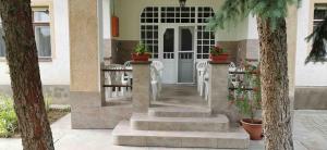 a porch with white chairs and a white door at István Apartman in Hajdúszoboszló