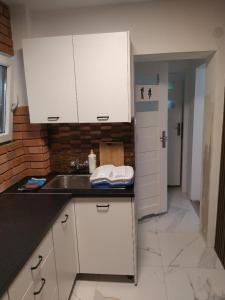 uma cozinha com armários brancos e um lavatório em Lake House Domek nr.11 Jezioro Nyskie em Skorochow