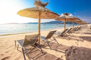 een rij stoelen en parasols op een strand bij Marinella, vue mer panoramique, superbe T2 plage à 150 m in Ajaccio