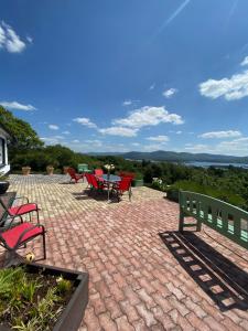 a patio with red chairs and a table with a view at Grenane Heights in Kenmare