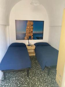 een slaapkamer met 2 bedden, een bureau en een schilderij bij Casa PAZIENZA in Monopoli