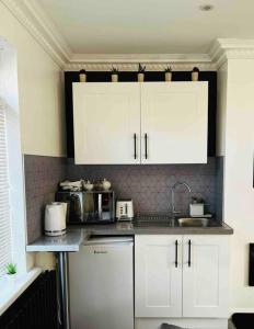 a kitchen with white cabinets and a microwave at The Lodge Annex - immaculate coastal property in Oystermouth