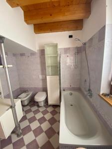 a bathroom with a large tub and a toilet at Red Chair House in Riva di Solto +13 photos