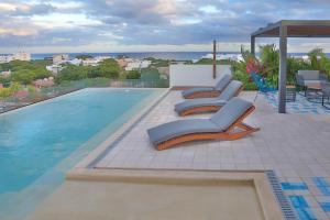 a group of lounge chairs sitting on a swimming pool at RIVA Playa Sur in Playa del Carmen
