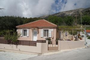 a small pink house with a white fence at Giannata House in Argostoli