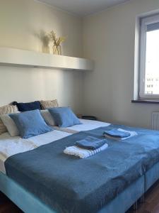 duże łóżko z niebieskimi kocami i poduszkami w obiekcie Prime Home SŁONECZNY w mieście Gdynia